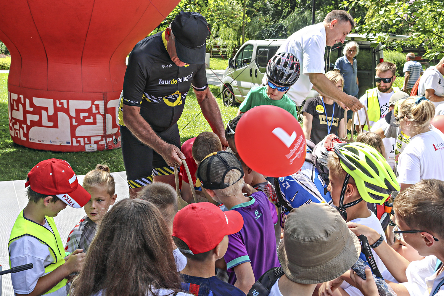 Dwukrotny medalista szosowych mistrzostw świata, organizator Tour de Pologne Czesław Lang oraz Poseł na Sejm RP rozdają gadżety dzieciom.