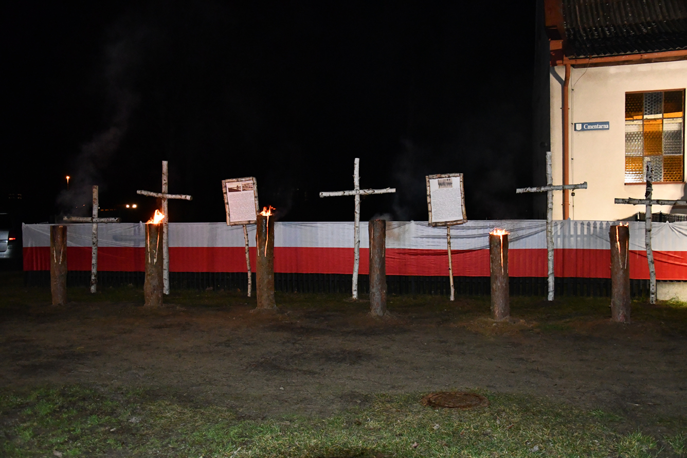 Dekoracja - na płocie flaga Polski, przed nią krzyże i tablice z informacjami o Powstaniu.