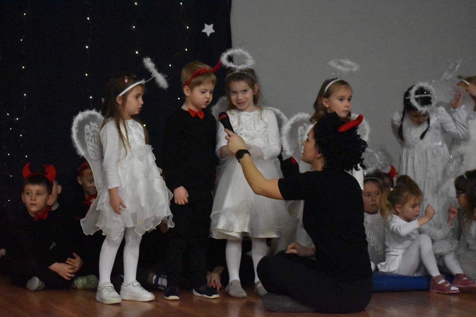 Dzieci w strojach aniołków i diabełków mówiące do mikrofonu wiersze 