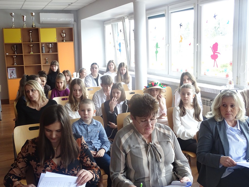 Zdjęcie przedstawia uczestników, nauczycieli oraz jury oceniające występy wszystkich uczestników konkursu recytatorskiego „Warszawska Syrenka”.