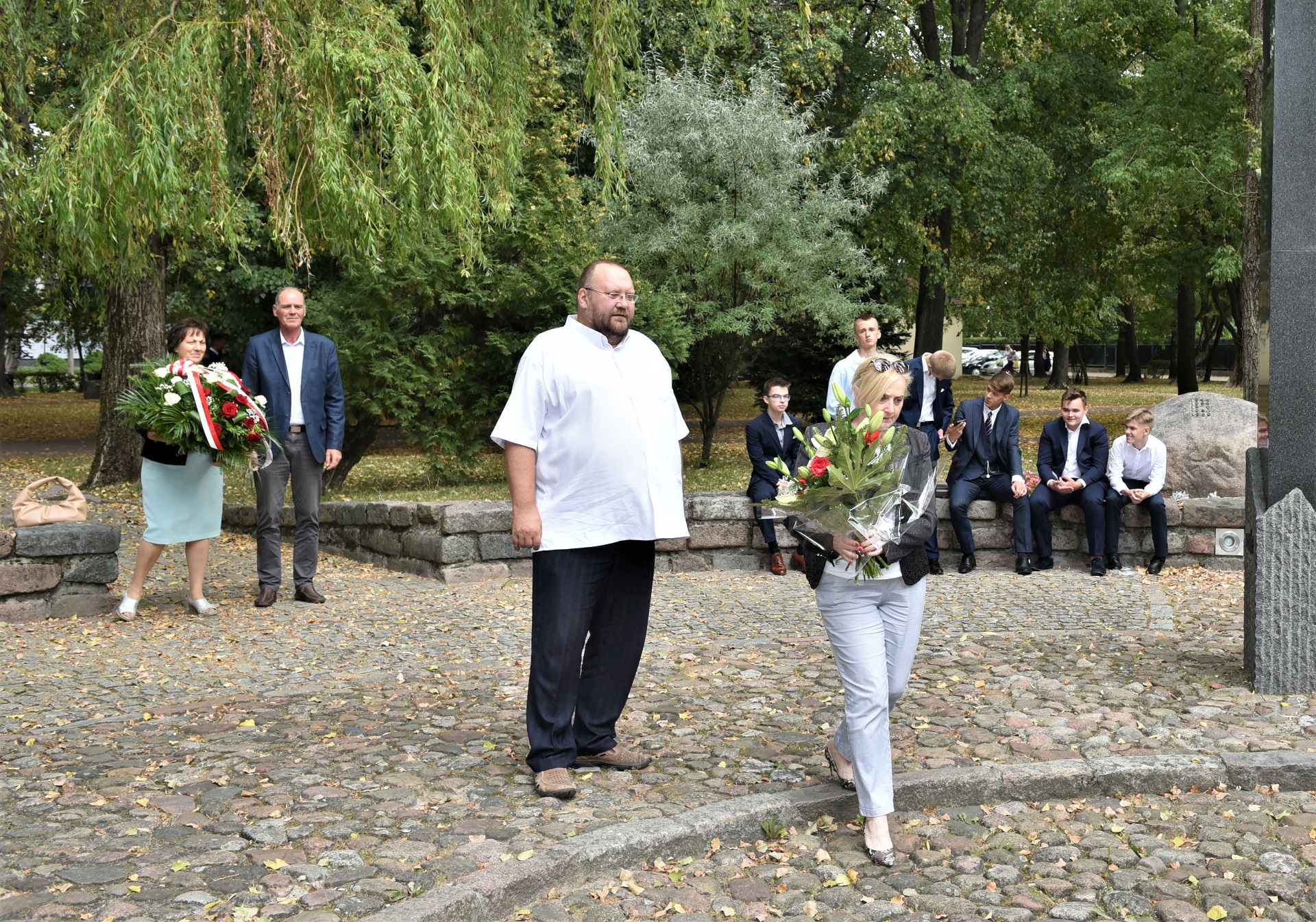 Moment złożenia kwiatów. Do kamienia w centralnej części pomnika zbliża się dyrektor biura senatora RP Waldemara Kraski - Joanna Malinowska.