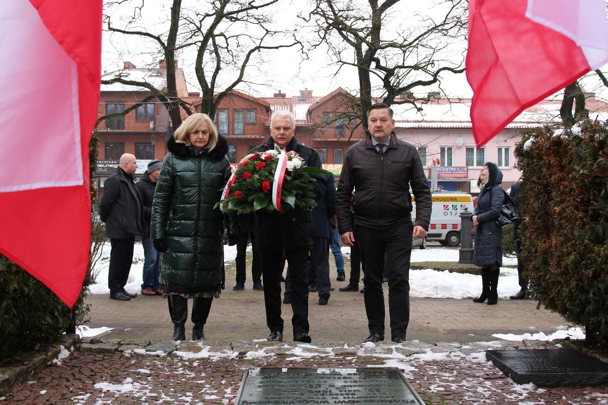 Na zdjęciu Senator RP Waldemar Kraska wraz z delegacja podchodzą do pomnika niosąc wiązankę z biało - czerwonych kwiatów