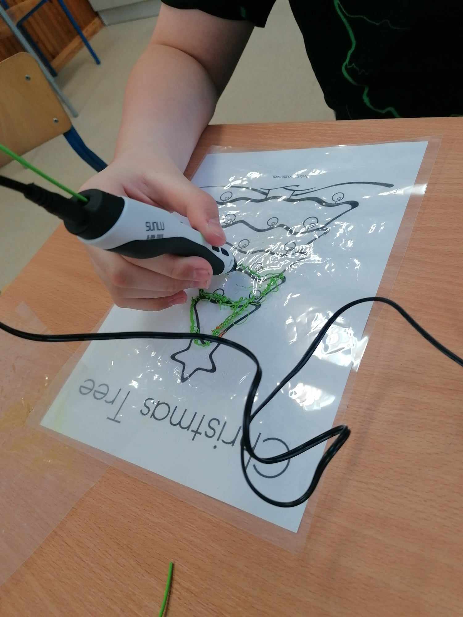 Uczeń wykonuje rysunek choinki za pomocą długopisu 3D.