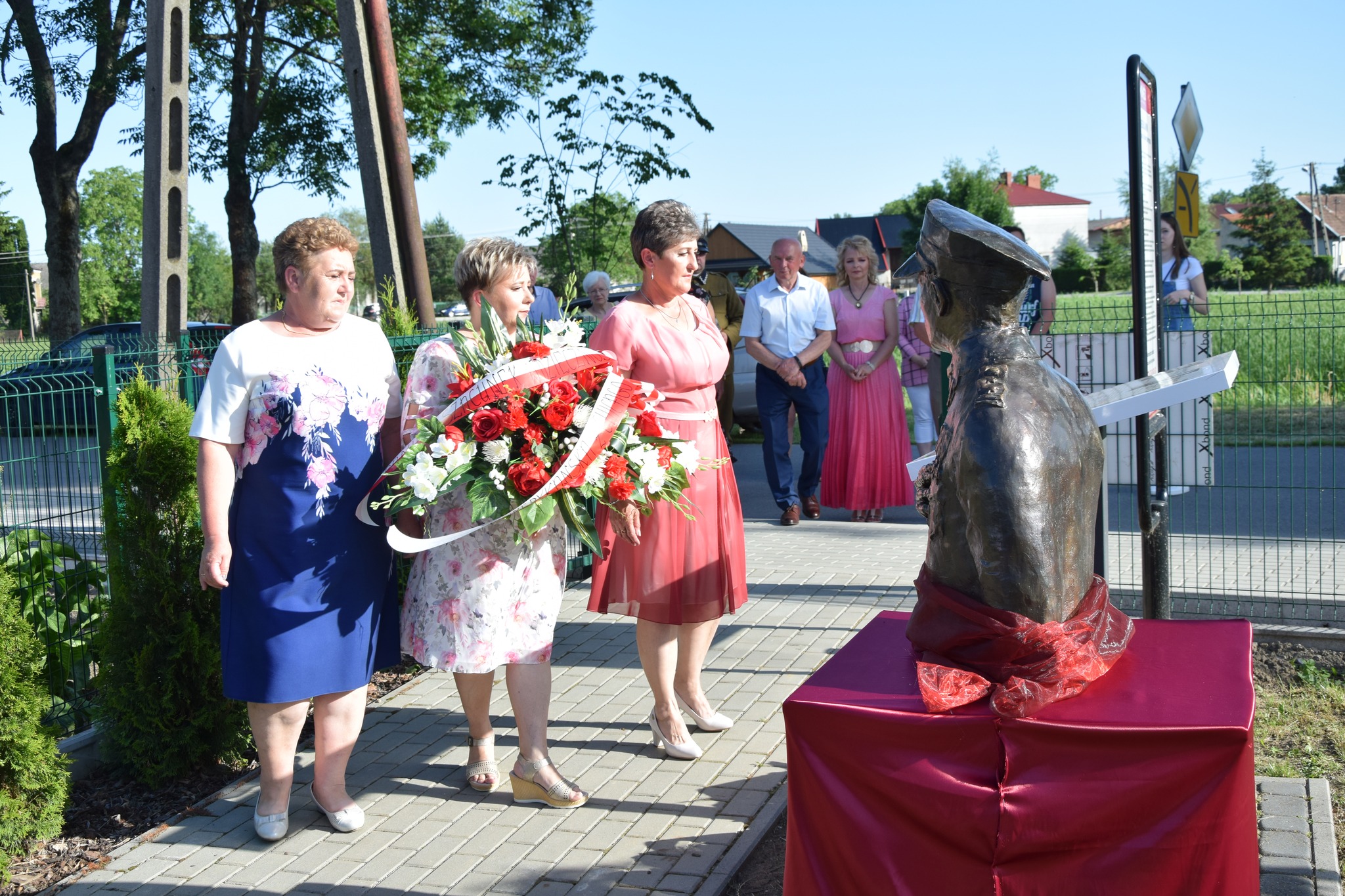 zdjęcie przedstawia członkinie Stowarzyszenia Miechowice Małe, które składają kwiaty przy tablicy pamiątkowej i pomniku Płk. Władysława Kabata.
