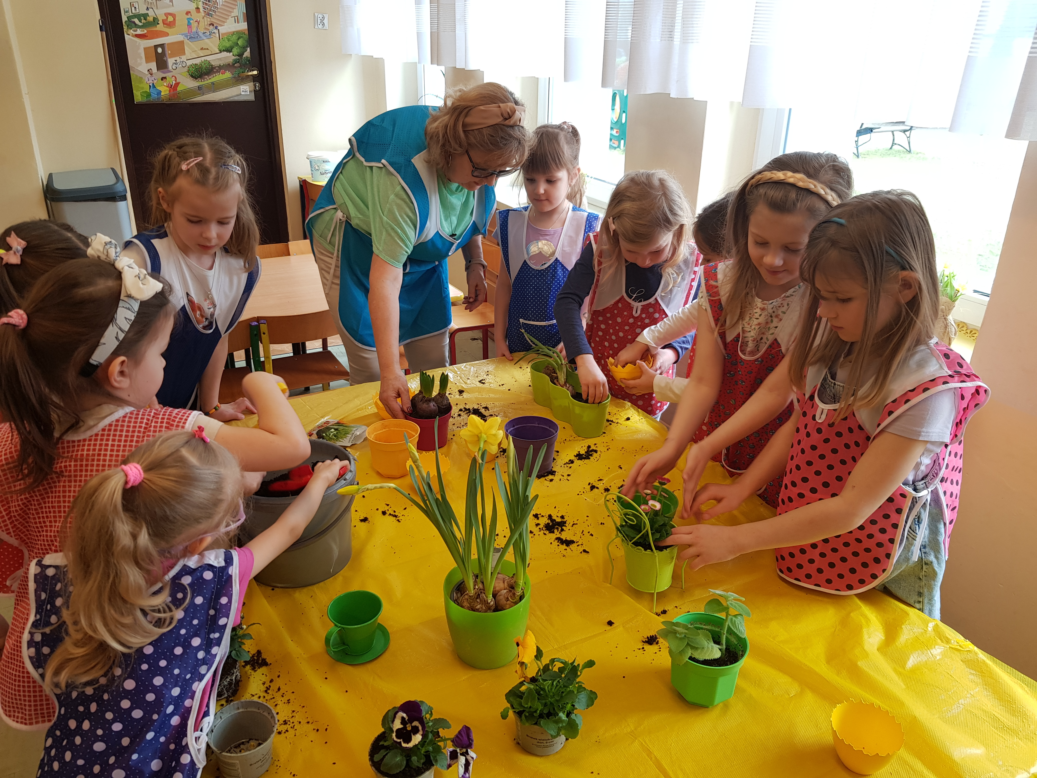 Dzieci zasypują ziemią cebulki kwiatów w doniczkach