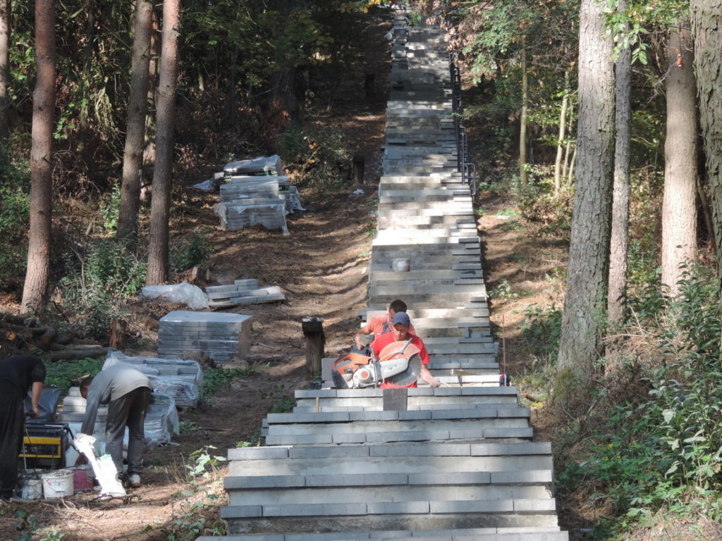 Na schodach prowadzących do pomnika układana jest kostka betonowa tarasowa trwa montaż nowych poręczy