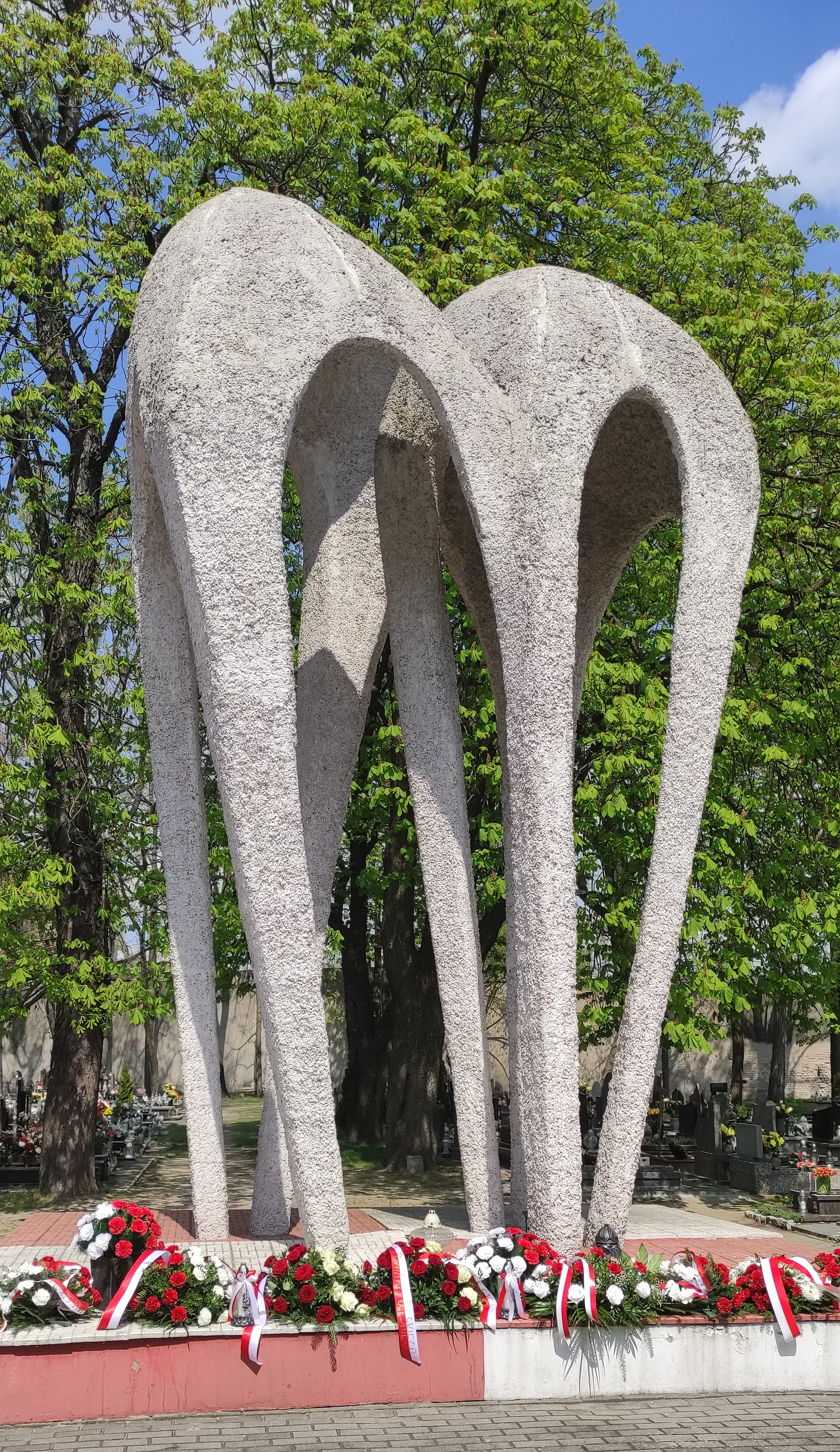Kwiaty złożone pod pomnikiem Lotników Polskich na cmentarzu komunalnym w Oleśnie