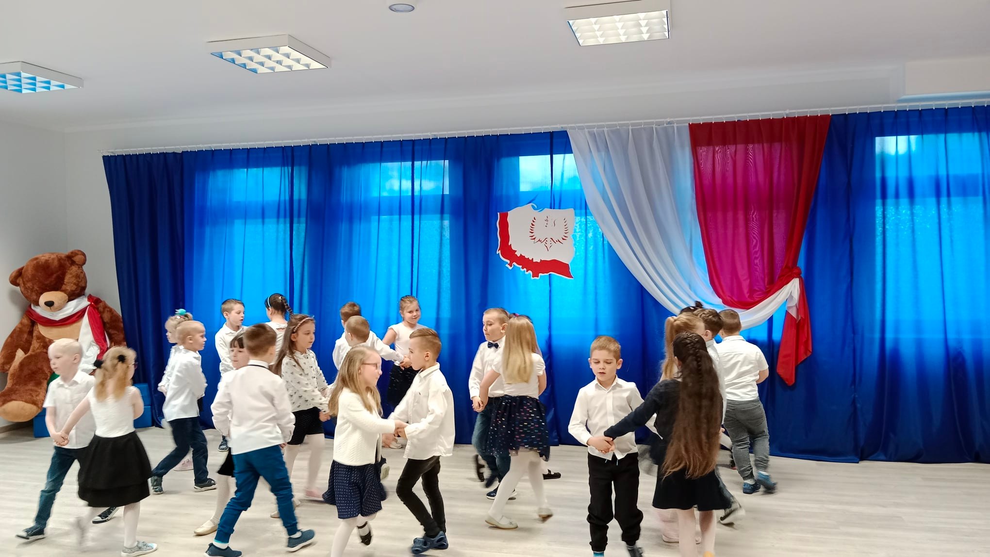Dzieci w strojach galowych tańczą