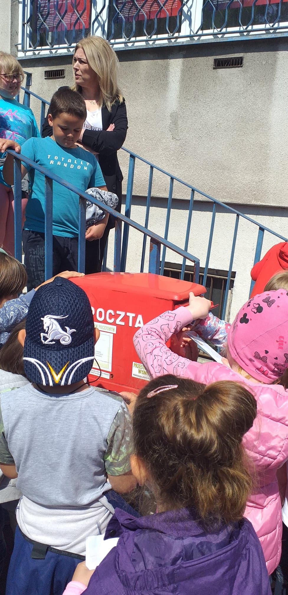 Dzieci wkładają ręce do czerwonej skrzynki pocztowej