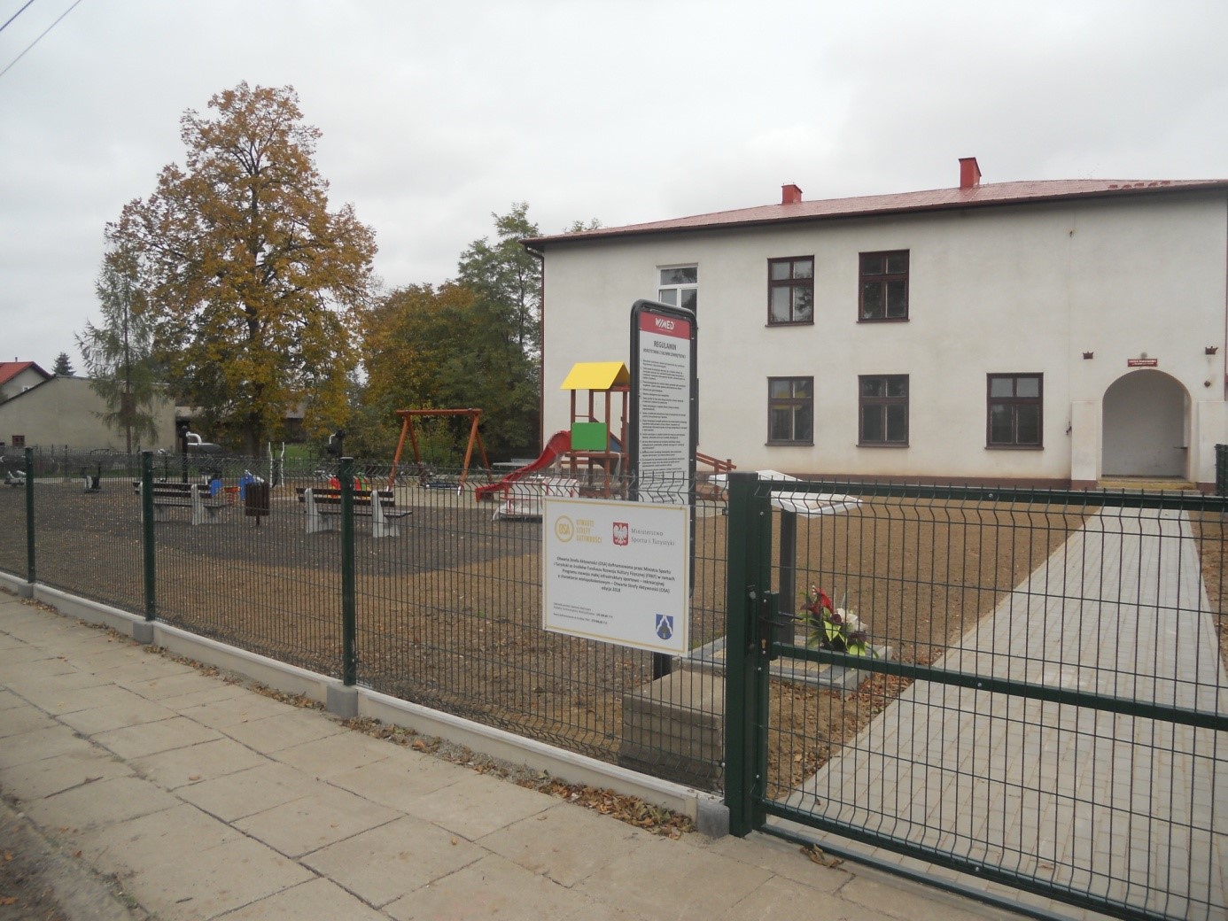 Plac zabaw w tle budynek kultury w Miechowicach Małych