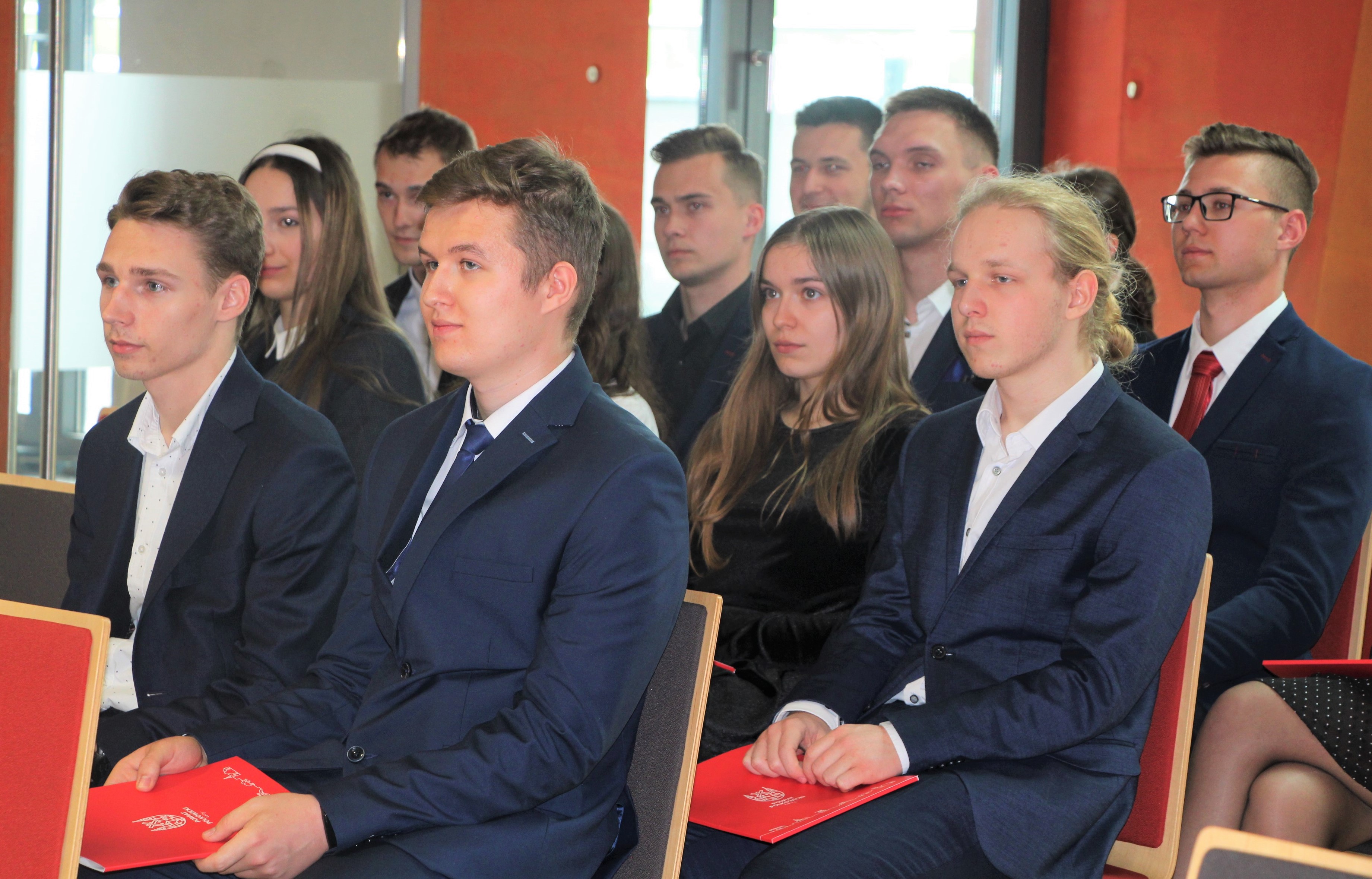 Grupa absolwentów siedzi na krzesłach w Sali Konferencyjnej podczas wręczania nagród Starosty Polkowickiego za najlepsze wyniki w nauce