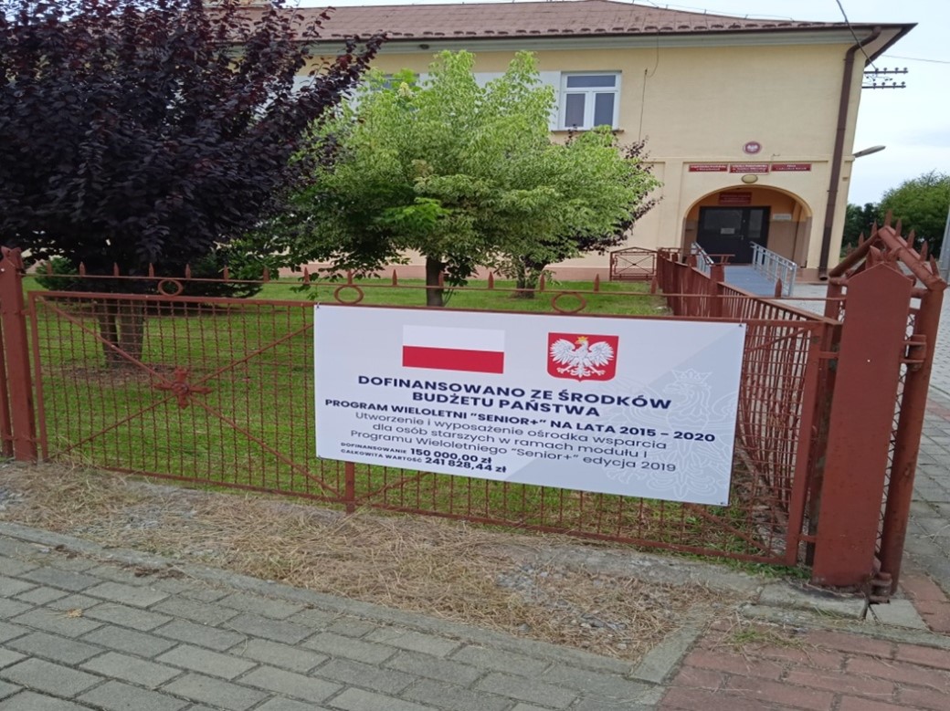 zdjęcie przedstawia tablicę informacyjną o dofinansowaniu zadania powstania Klubu Seniora w miejscowosci Jadowniki Mokre.