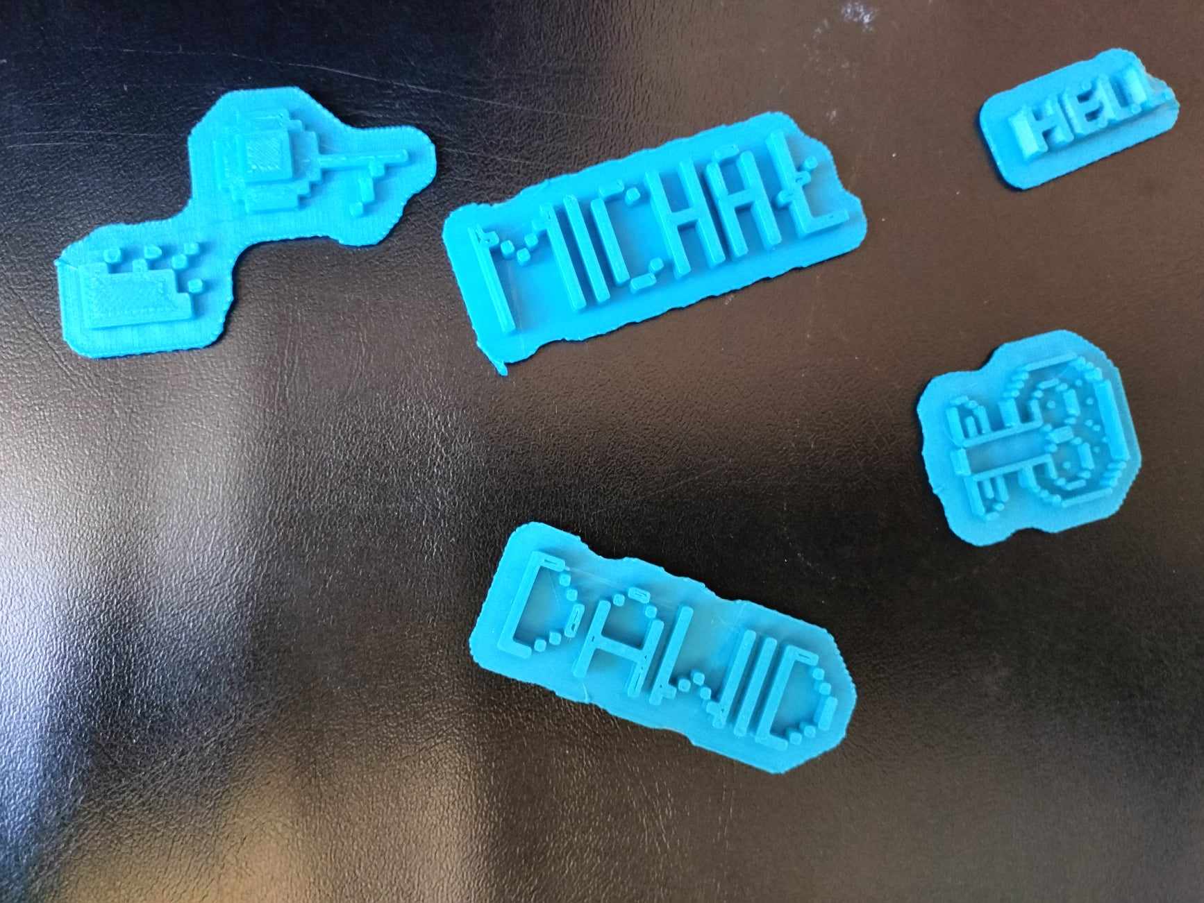 Pięć niebieskich breloczków wykonanych na drukarce 3D.