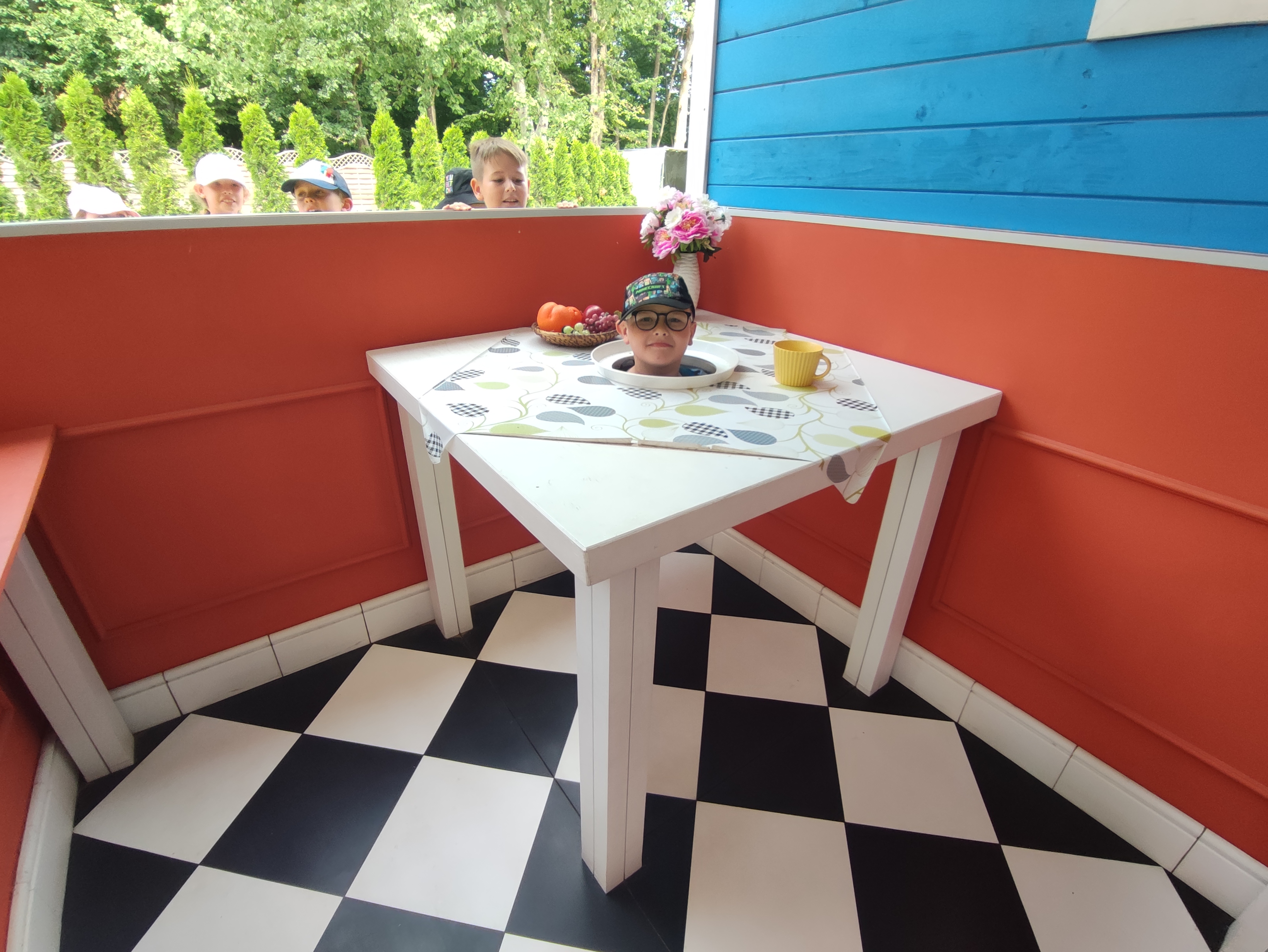 Zdjęcie przedstawia dziecko pozujące w niewidzialnym stoliku w Farmie Iluzji