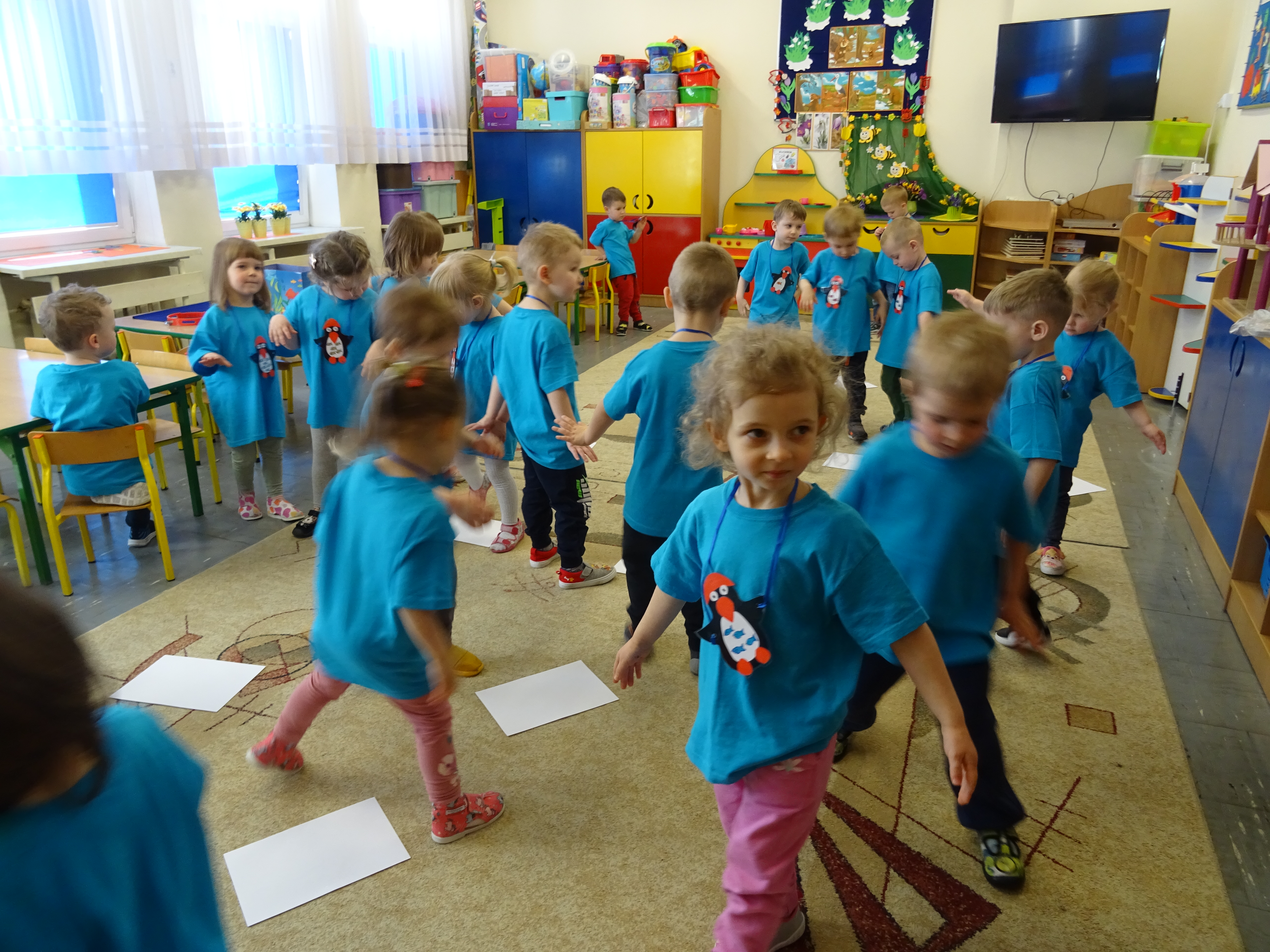 Dzieci w niebieskich koszulkach podczas zabawy w pingwinki 
