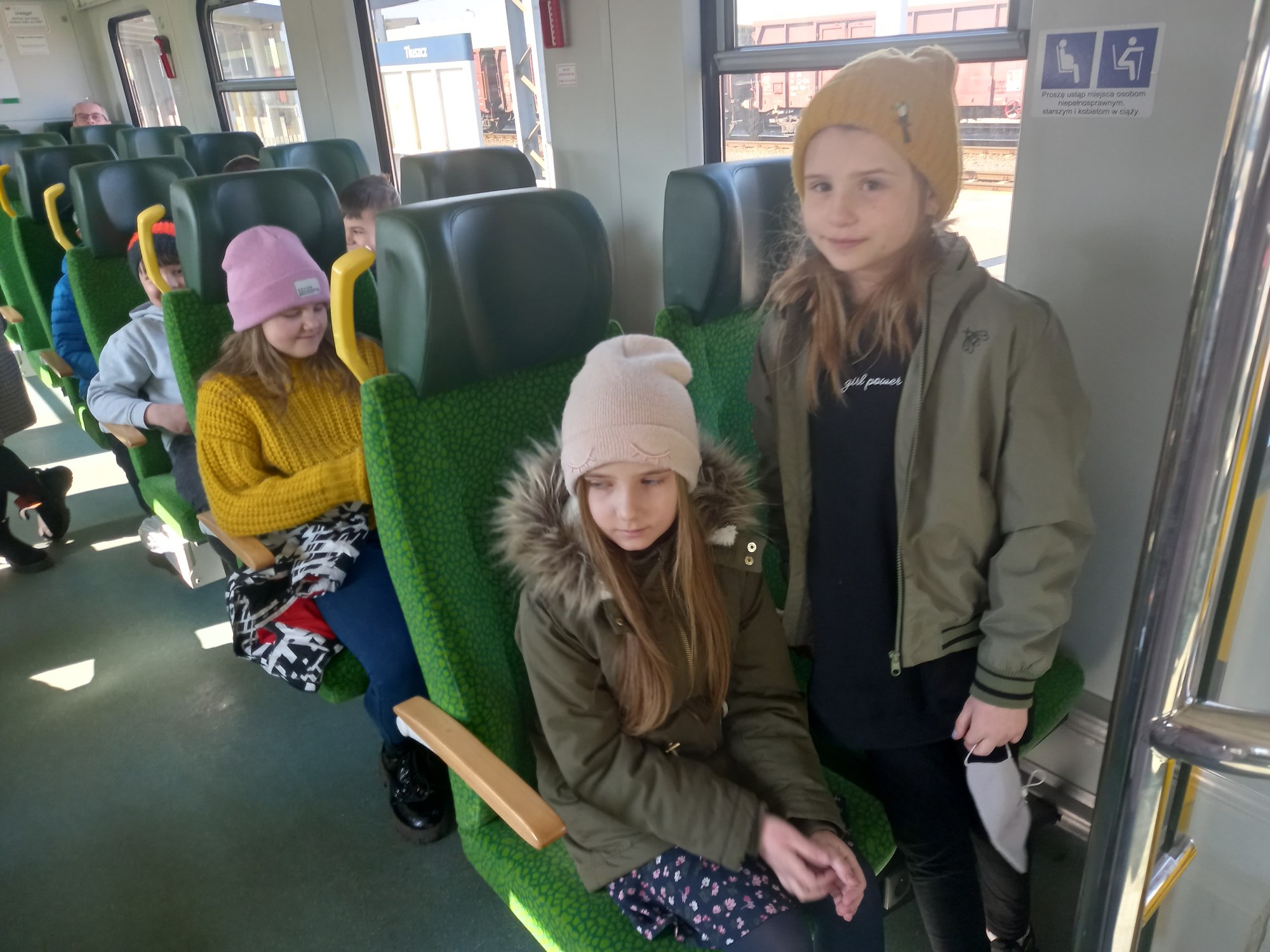 Dzieci siedzą na zielonych fotelach w pociągu