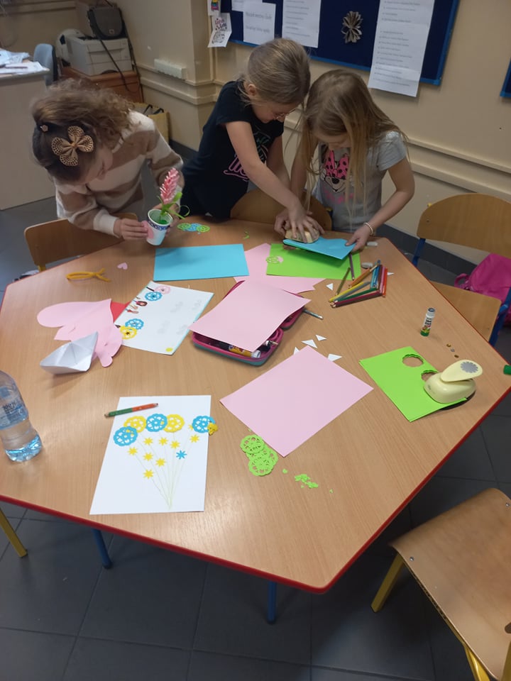 Dzieci robią z kolorowego papieru prace plastyczne