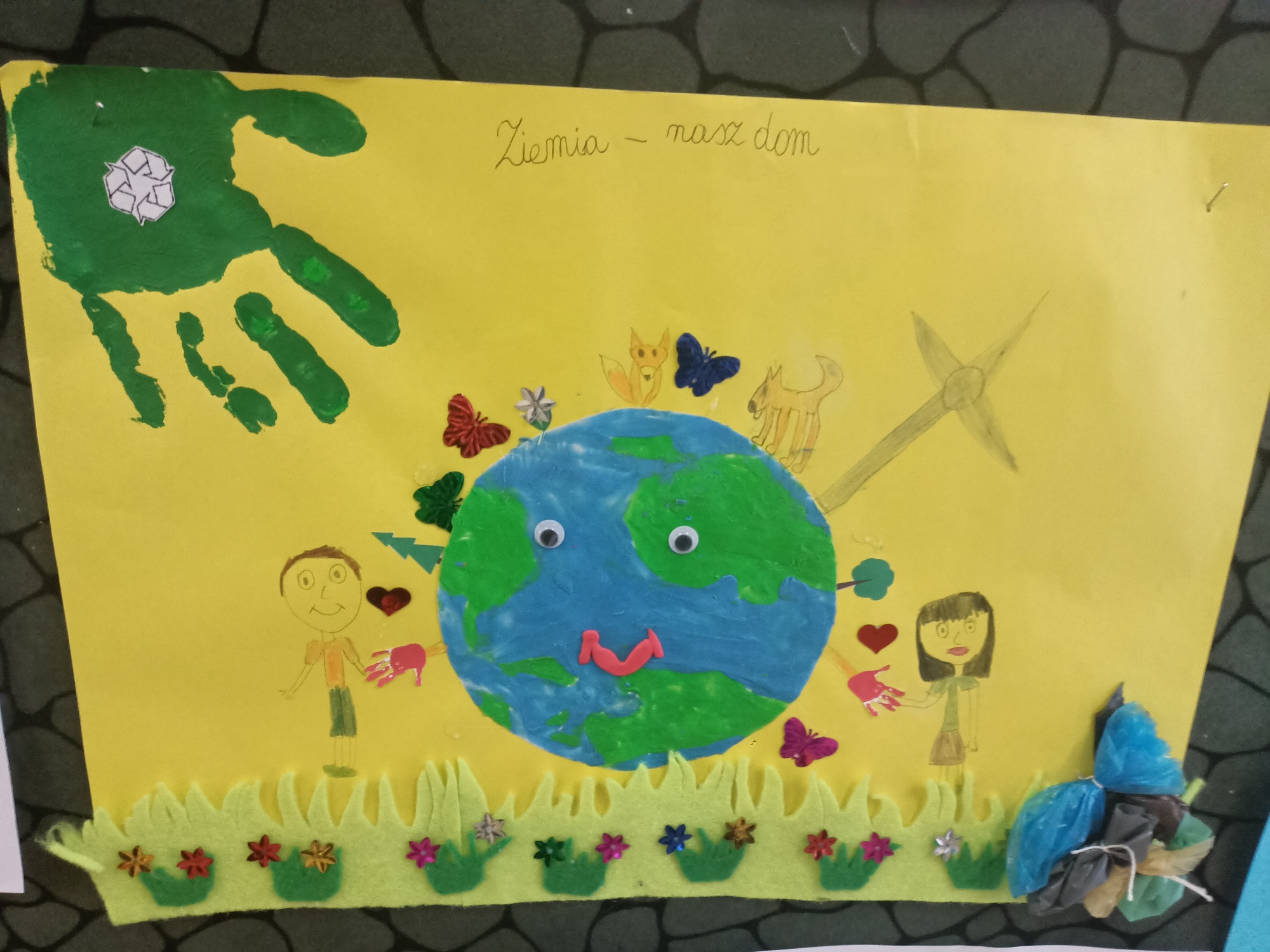 Obrazek z namalowaną planetą Ziemia oraz zielonym odciskiem ręki