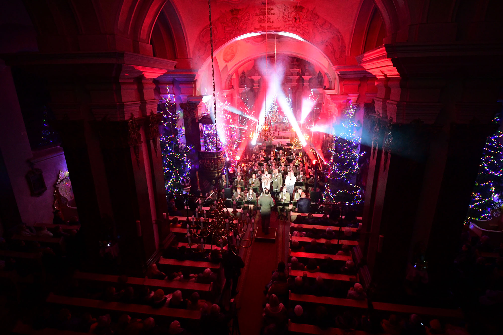 Iluminacja kościoła podczas koncertu, na wprost ołtarz i orkiestra, po bokach widownia.