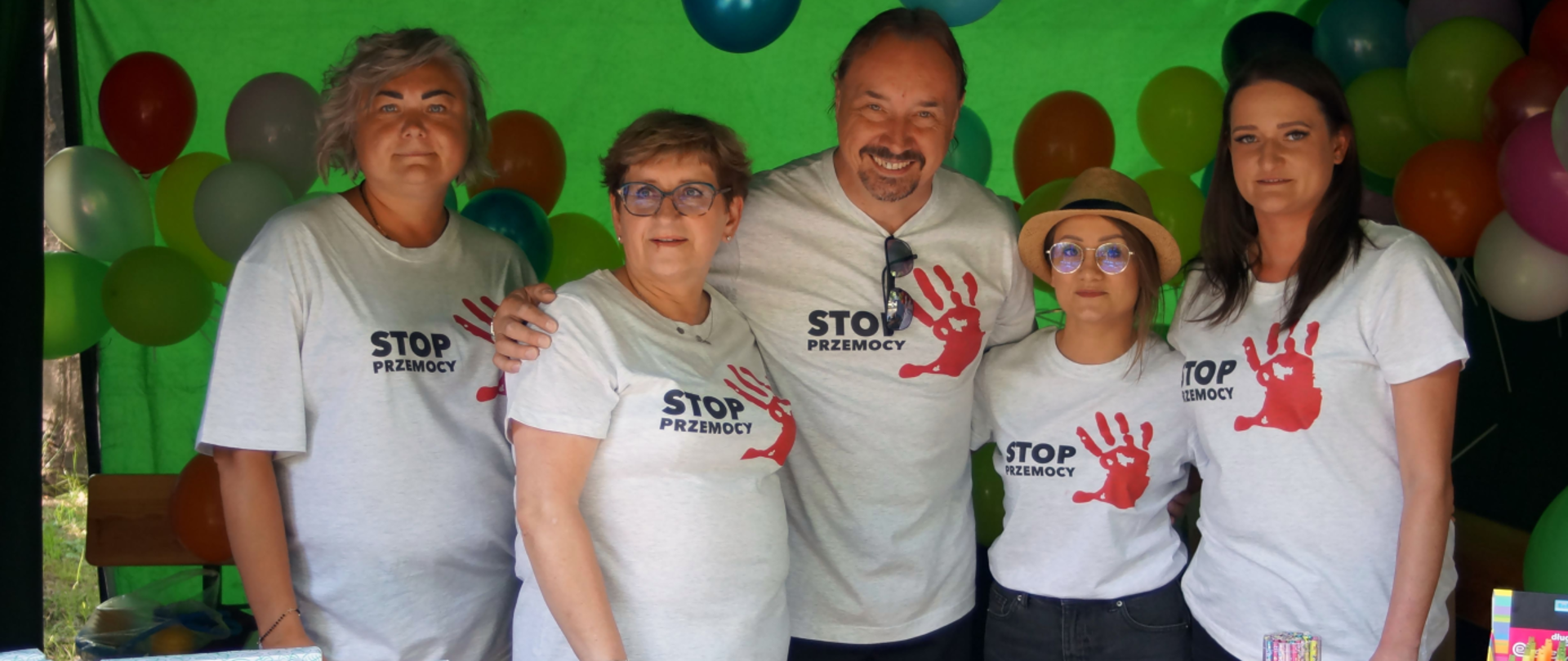 Grupa ludzi za stołem z broszurami w koszulkach stop przemocy