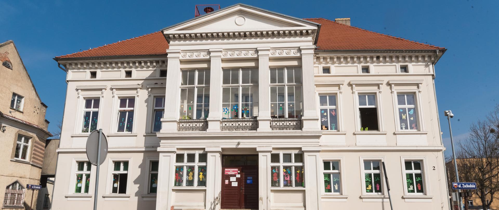 jasny budynek z dużymi oknami, na tle błękitnego nieba