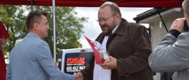 Na scenie przewodniczący Rady Powiatu Sokołowskiego Jacek Odziemczyk wręcza upominek prowadzącemu imprezę