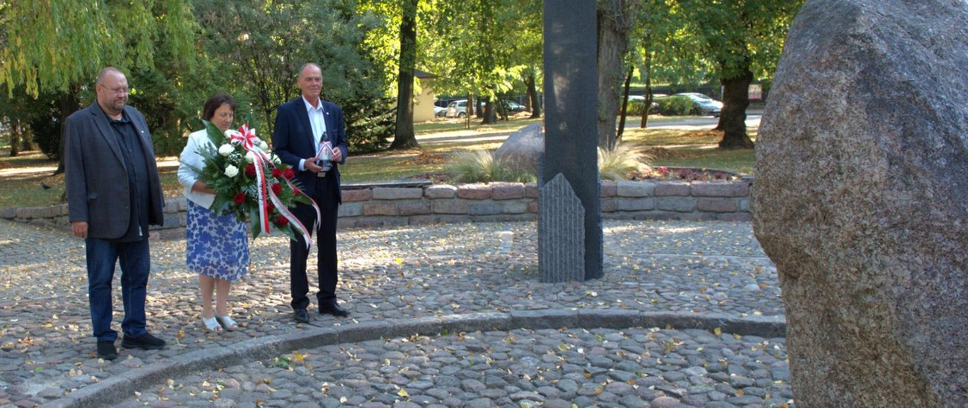 Na zdjęciu widać delegację powiatu sokołowskiego, która zmierza w kierunku centralnej części pomnika "Czynu Niepodległościowego", który stanowi przecięty poprzecznie na pół owalny głaz z napisem Bóg, Honor, Ojczyzna. W tle park Adama Mickiewicza w Sokołowie Podlaskim.