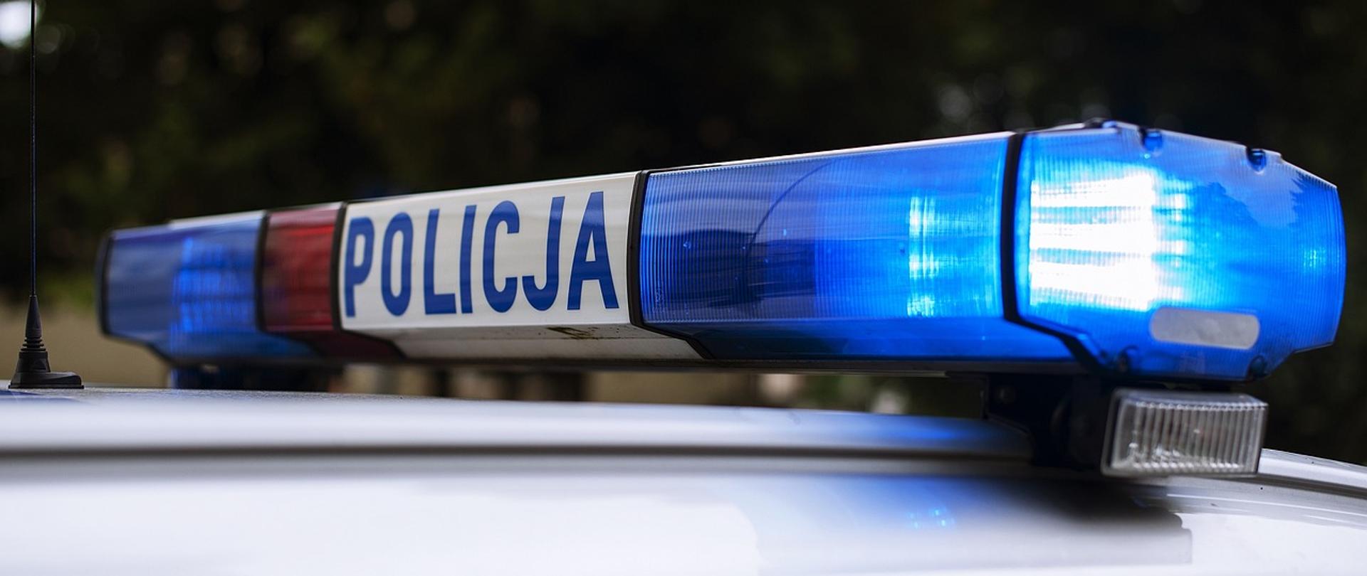 Sygnalizator świetlny na dachu radiowozu policyjnego. Jedno ze świateł sygnalizatora świeci na niebiesko