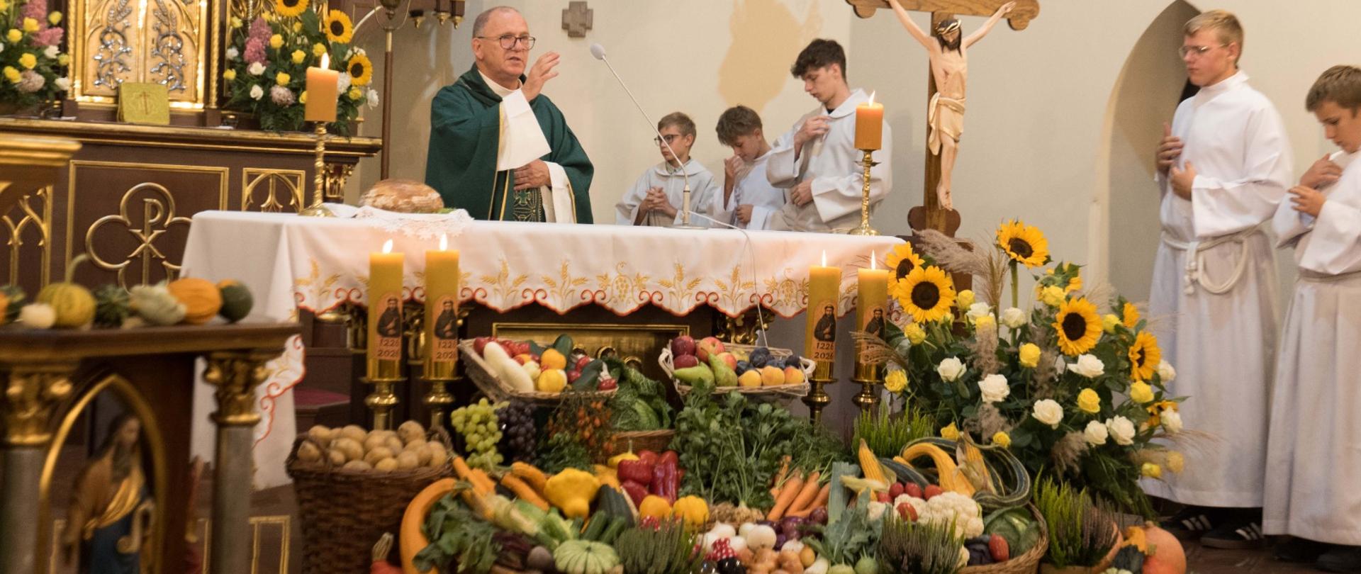 Ksiądz przy ołtarzu pełnym płodów rolnych