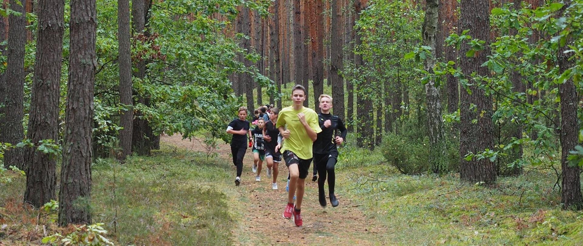Grupa chłopców biegnie leśną ścieżką