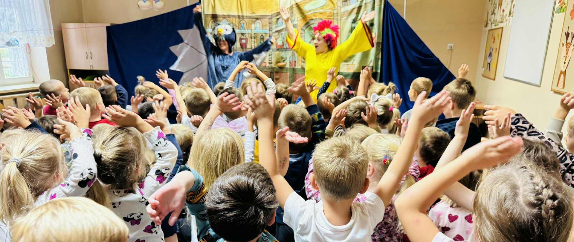 Grupa dzieci ogląda przedstawienie teatralne "Kaczka Cudaczka"