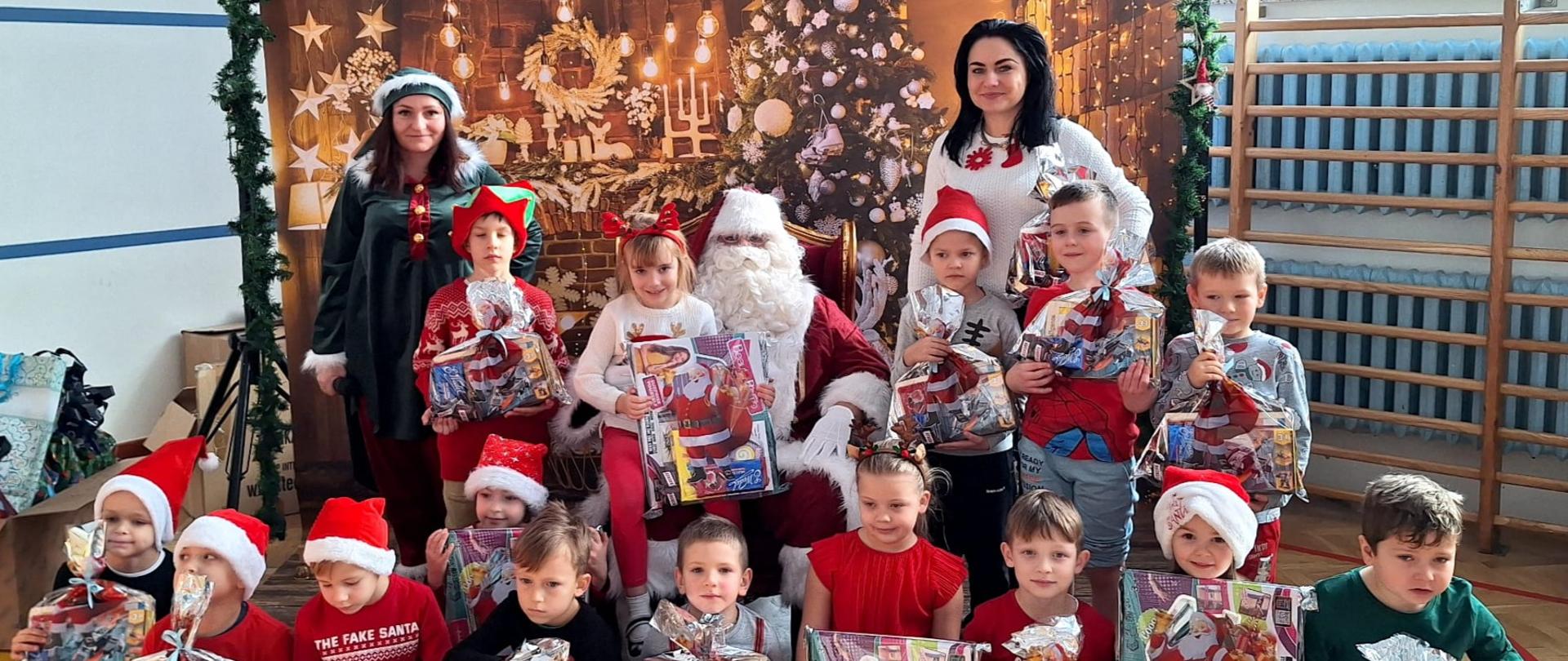 Uczniowie klasy 2b z Mikołajem, na tle świątecznej dekoracji .