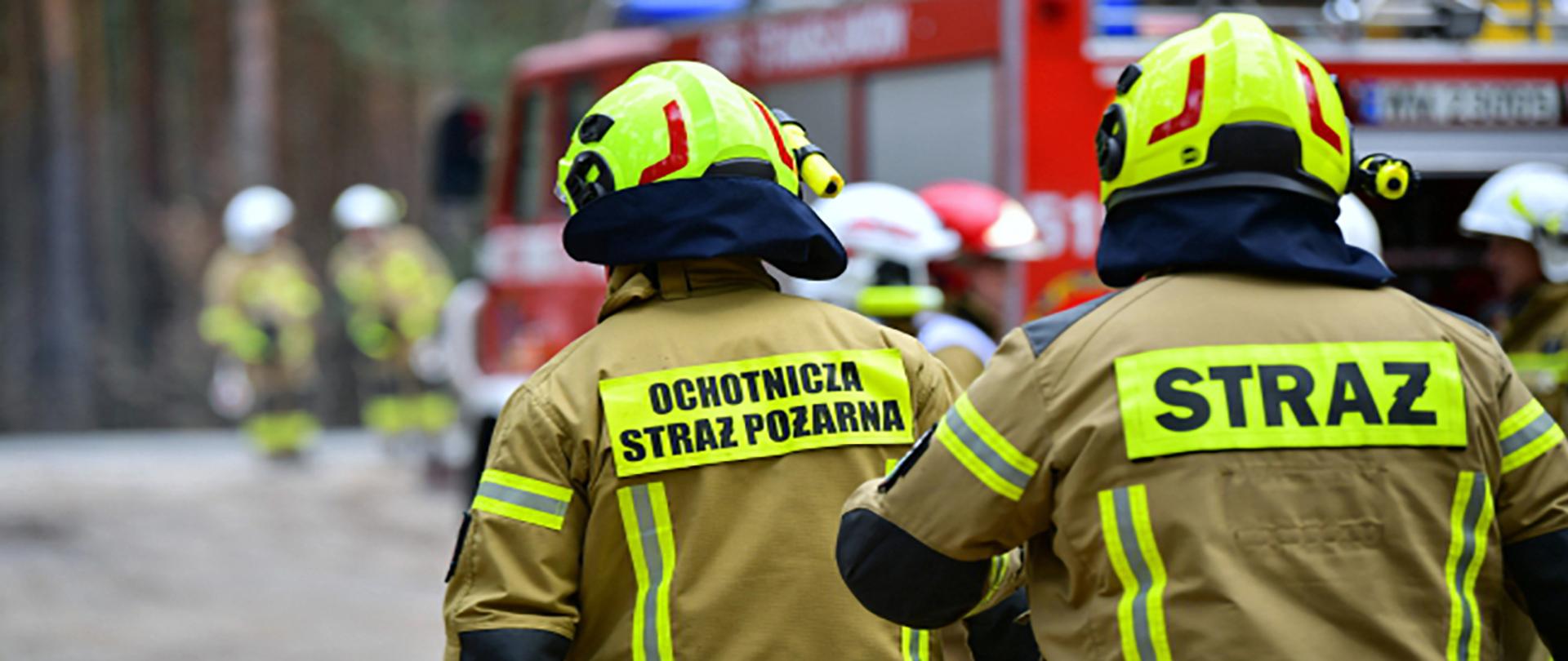 Dwóch strażaków OSP w jasnych strojach roboczych