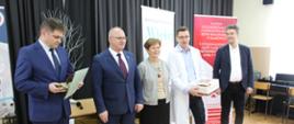 Przedstawiciel Uniwersytetu Przyrodniczo - Humanistycznego odbiera nagrodę Starosty Hajnowskiego - obok niej do zdjęcia pozują Starosta Hajnowski, Zastępca Burmistrza Miasta, Naczelnik Wydziału Spraw Społecznych i Zastępca Dyrektora II Liceum