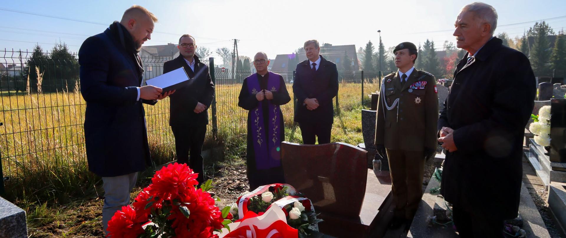 Przedstawiciele władz wojewódzkich i powiatowych, Wójt Gminy Kobiór oraz proboszcz parafii podczas uroczystości przy grobie wojennym Zdzisława Ołtuszewskiego na cmentarzu w Kobiórze. Przy grobie złożono kwiaty i wieńce w biało-czerwonych barwach.