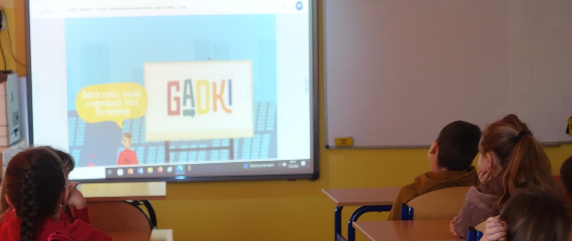 Uczniowie w sali lekcyjnej oglądają film animowany "Gadki z Maksem"