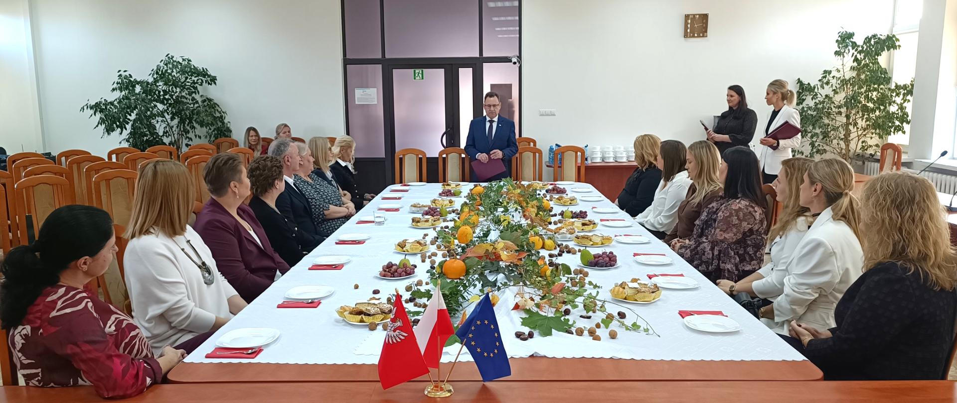 Na zdjęciu przy uroczyście nakrytym stole siedzą przedstawiciele szkół w głębi widzimy przemawiającego starostę sokołowskiego.