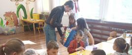 Dwóch chłopców przedstawicieli Samorządu Uczniowskiego częstuje cukierkami dziewczynki z oddziału przedszkolnego