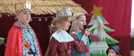Przedszkolaki odgrywają jasełka w przebraniach świątecznych, w tle szopka
