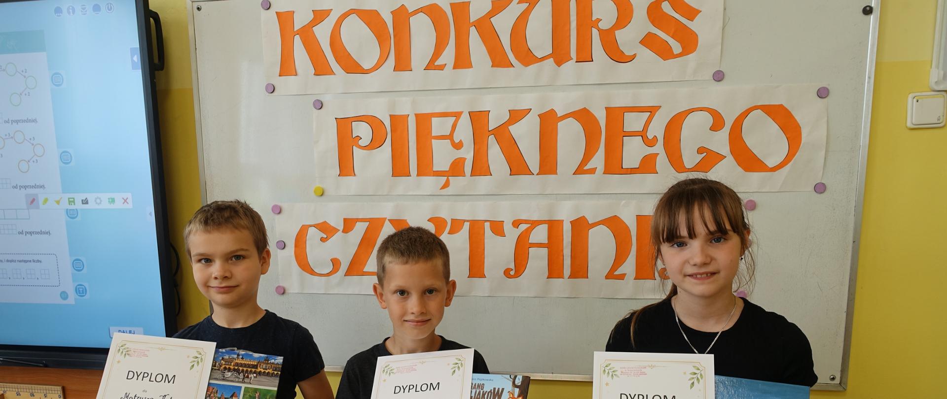 Uczniowie nagrodzeni w konkursie stoją z dyplomami i nagrodami książkowymi