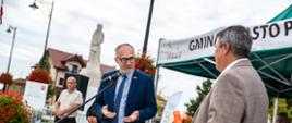 Starosta Powiatu Proszowickiego przed mikrofonem zwraca się do stojacego obok Burmistrza Gminy i Miasta Proszowice