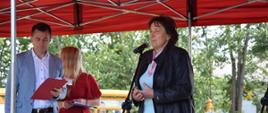 Na scenie przemawia starosta sokołowski Elżbieta Sadowska, w tle prowadzący imprezę pracownik Caritas Paweł Królasik