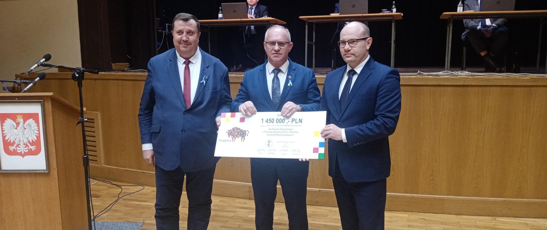 Radny Sejmiku Województwa Mikołaj Janowski, Starosta Hajnowski Andrzej Skiepko oraz Marszałek Artur Kosicki pozują do zdjęcia z promesą