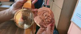 Dwa złote medale trzymane w dłoni za udział w biegach przeszkodowych pana Piotra Prusaka