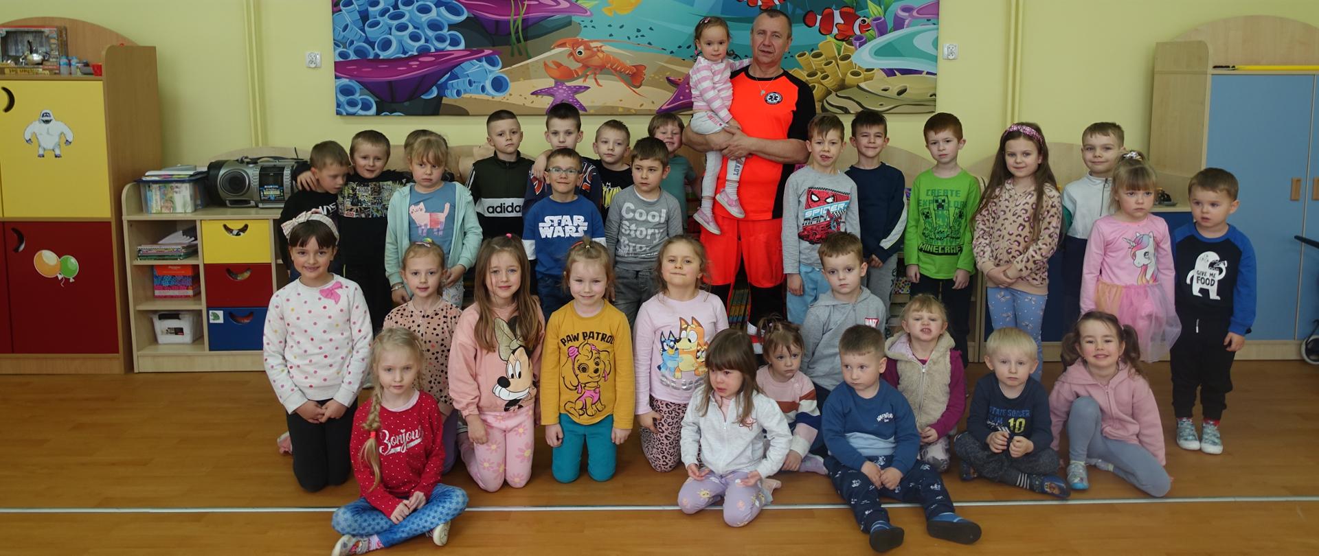 Pamiątkowe zdjęcie przedszkolaków i pana ratownika medycznego.