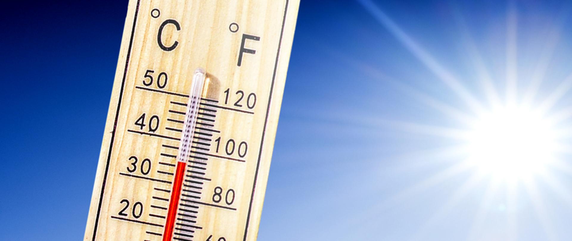 Na zdjęciu znajduje się termometr wskazujący temperaturę powyżej 30 stopni Celsjusza. W tle słońce i błękitne niebo. 
