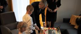 Starosta razem z chłopcem kroją tort. Obok starosty stoi kobieta. Obok chłopca stoi mała dziewczynka.