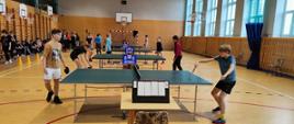 Uczestnicy w trakcie zawodów - rozgrywki przy stołach do tenisa