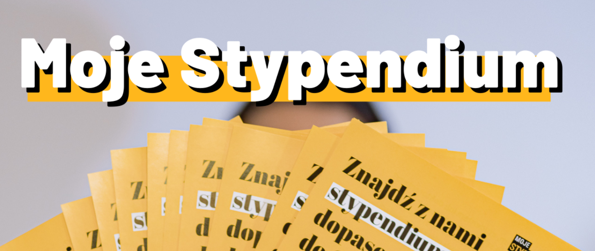 Grafika z napisem -Moje Stypendium. W żółtej kolorystyce, w tle zdjęcie z kuponami.