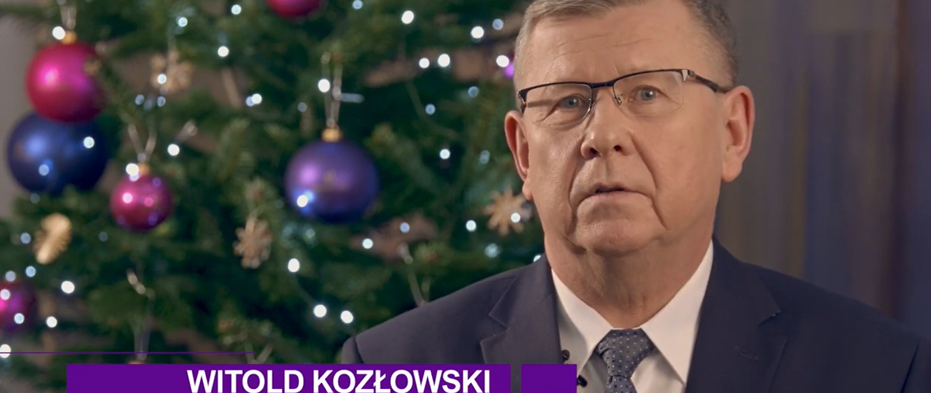 Zdjęcie przedstawia zbliżenie twarzy Marszałka Województwa Małopolskiego Witolda Kozłowskiego, w tle przyozdobiona choinka.